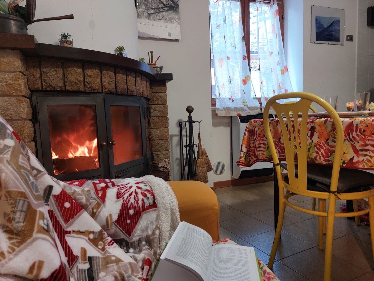 Camino acceso, coperta e libro nella zona giorno