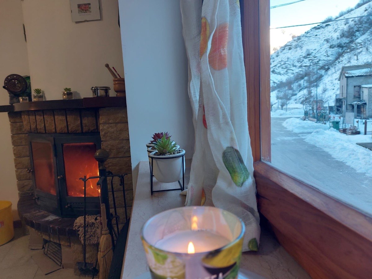 Camino acceso e vista sulla neve dalla finestra